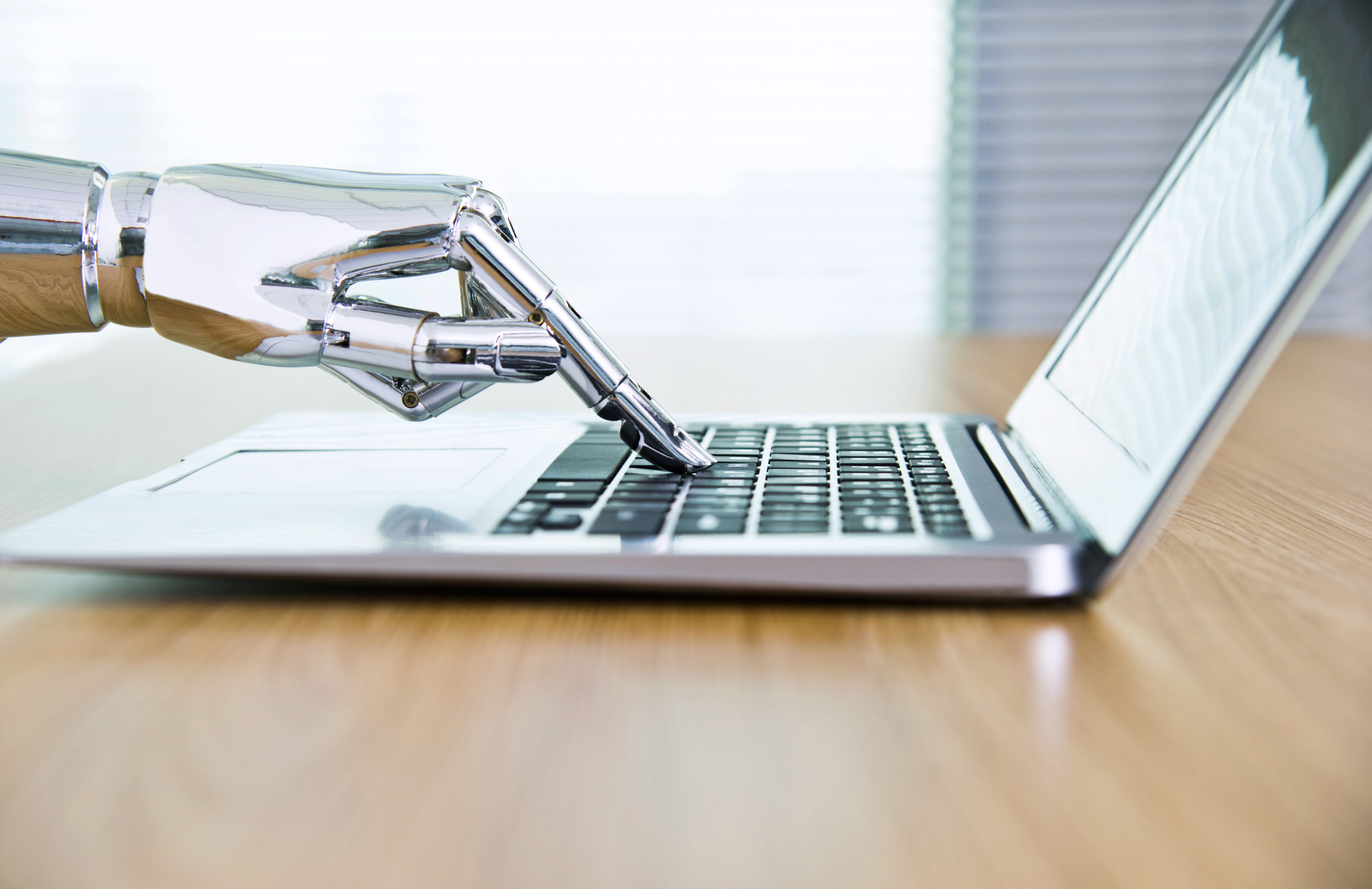 Roboterhand drückt eine Taste auf einem Notebook.